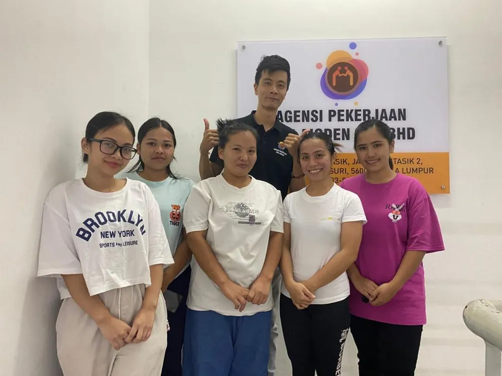 Era Moden staff and four helpers standing in front of the agency signboard at the Kuala Lumpur office